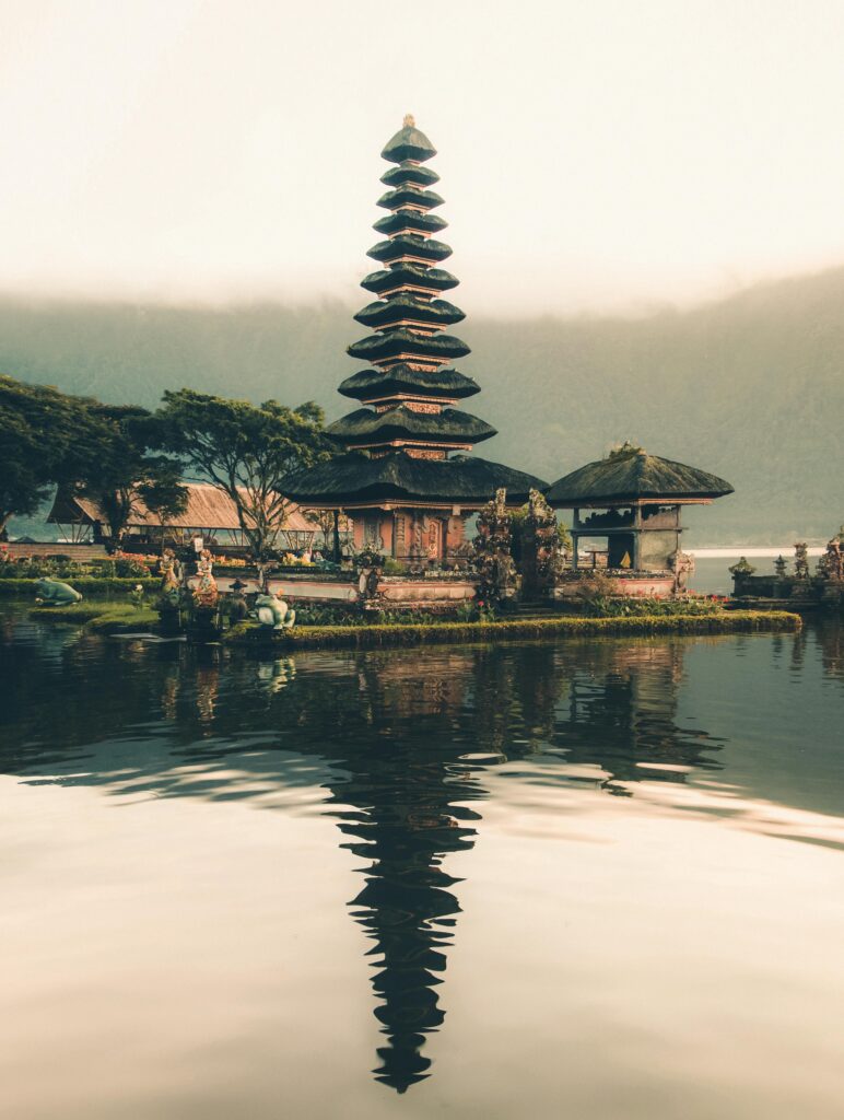 A serene view of Ulun Danu Beratan Temple with reflections on the water at sunrise, Bali.